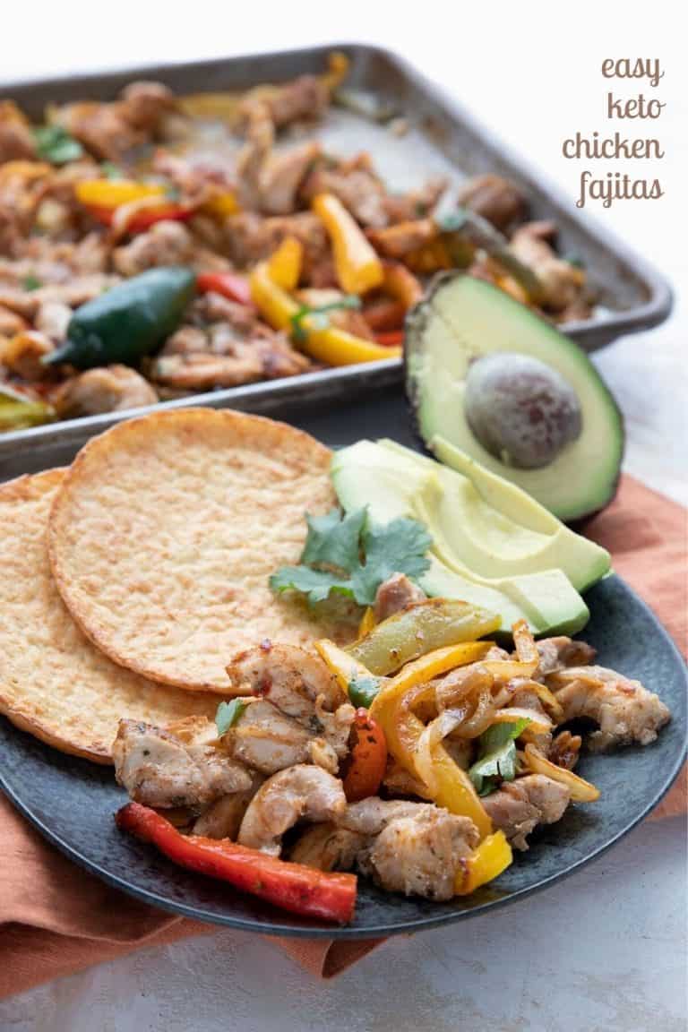 Titled image of sheet pan keto chicken fajitas, with some on a black plate in front of the sheet pan.