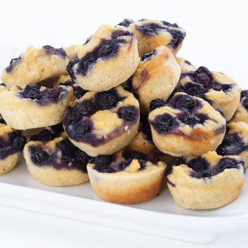 Keto blueberry pancake bites piled high on a white plate.