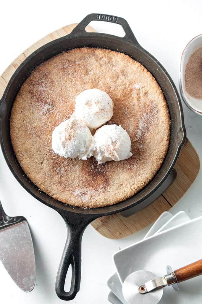 Top down image of a keto skillet cookie in a cast iron pan, with scoops of vanilla ice cream on top. 