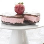 Keto Mini Strawberry Cheesecake for Two on a white cake stand with a strawberry on top.