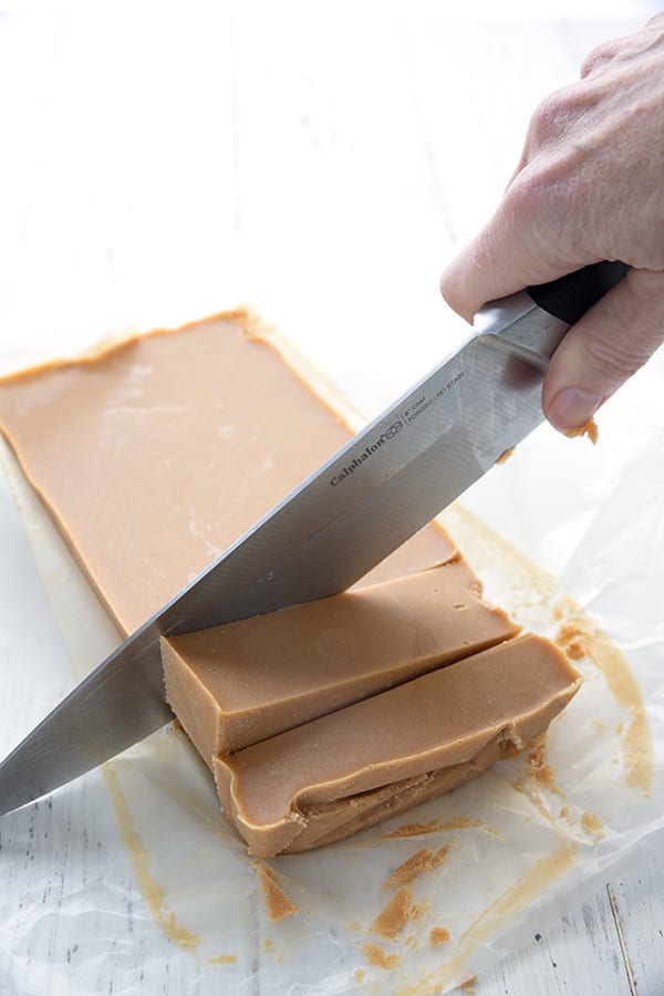 A brick of keto peanut butter fudge being cut into squares