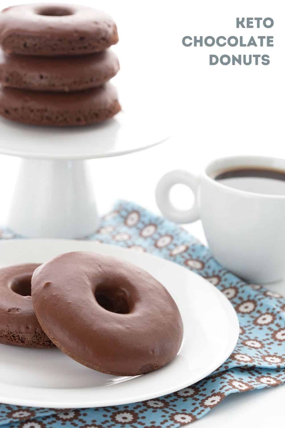Titled image of keto chocolate donuts on a white plate over a blue patterned napkin, with a cup of coffee