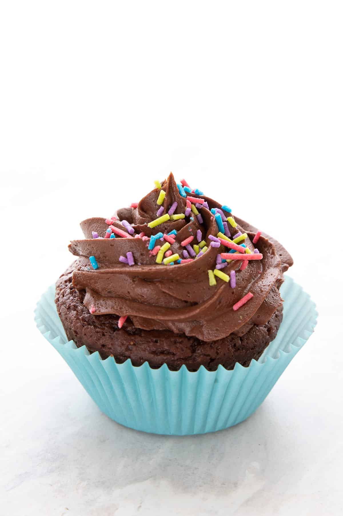 Kremet keto-sjokoladefrosting på en sjokoladecupcake i en blå cupcakeform. 