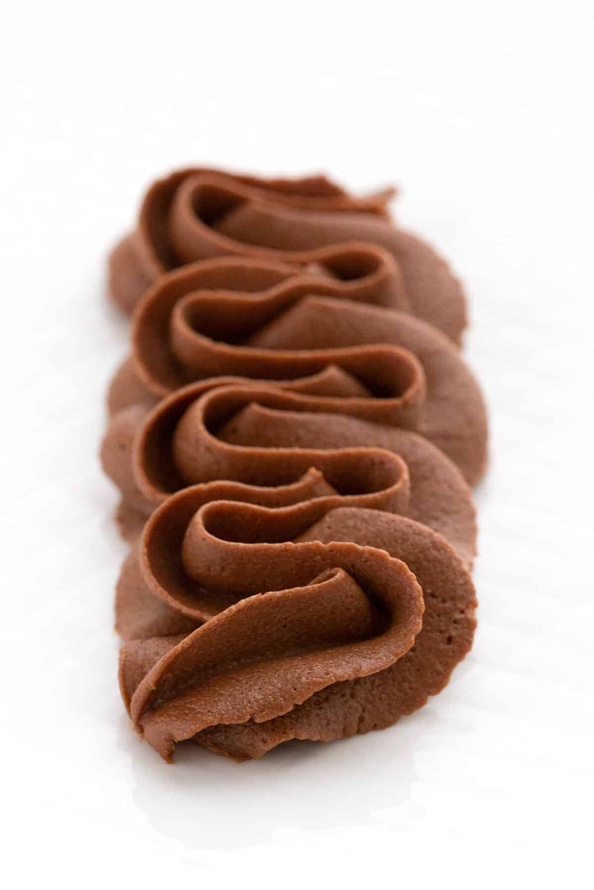 Keto-sjokoladeglasur påføres dekorativt på en hvit tallerken. 