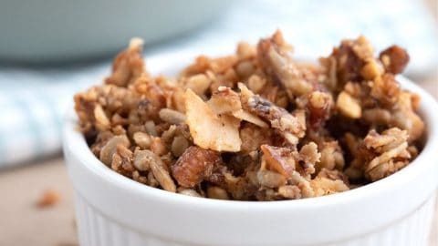 Low carb granola in a white ramekin on a brown table.