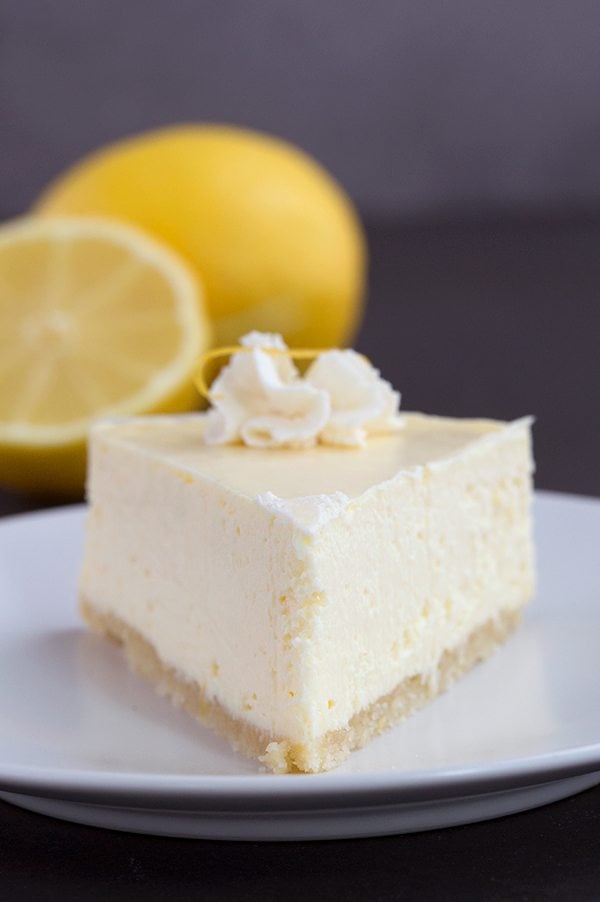 Keto Instant Pot Lemon Cheesecake on a white plate with cut lemons 