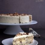 Keto Italian Cream Cake Recipe - a slice of cake on a white plate with the large cake in behind.
