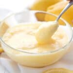 Titled Pinterest image of a small spoon digging into a glass bowl filled with keto lemon curd.