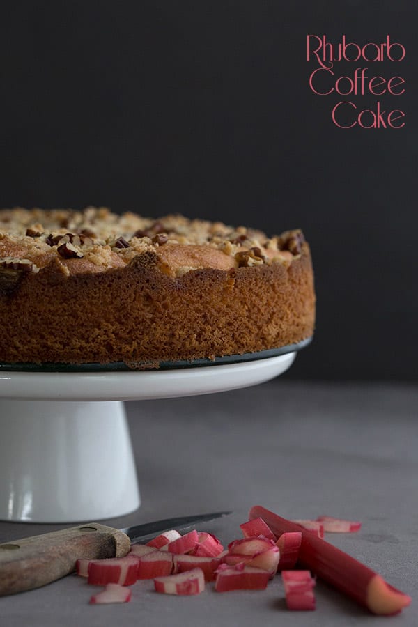 Low Carb Rhubarb Coffee Cake with pecans on a white cake stand