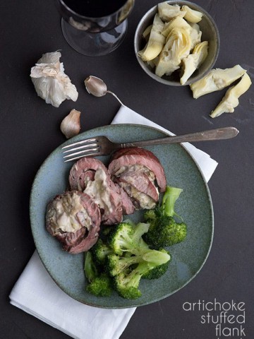 Keto artichoke stuffed flank steak on a plate with broccoli, along with a glass of wine.
