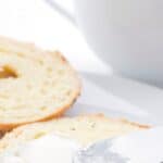 Titled image of a knife spreading cream cheese on a keto bagel.