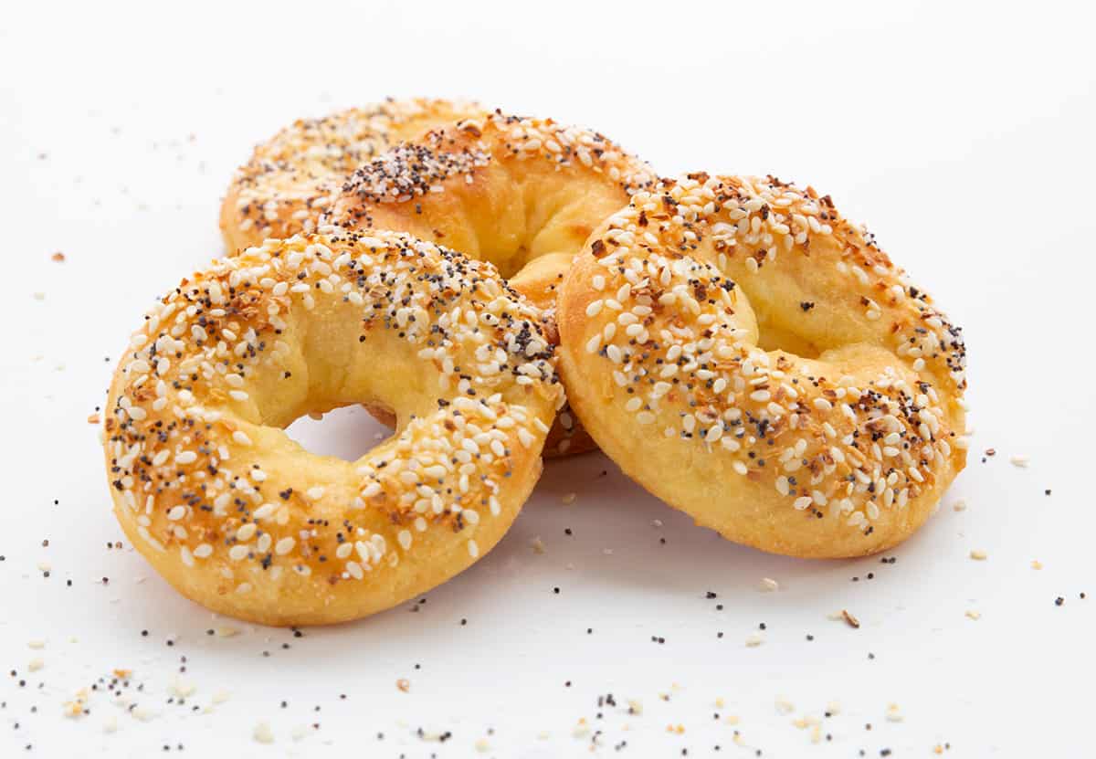 Three keto bagels with everything seasoning in a pile on a white background. 