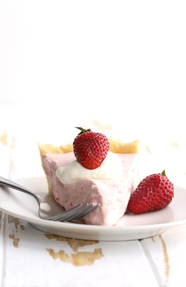A single slice of low carb Strawberry Cream Pie with whipped cream and a fork