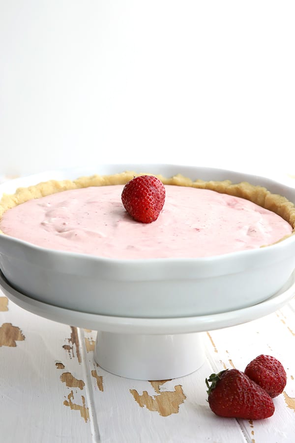 Strawberry cream pie in a white pie plate on a cake stand