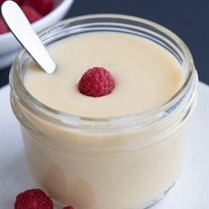 Close up shot of Easy Sugar Free Condensed Milk in a jar with a raspberry on top.