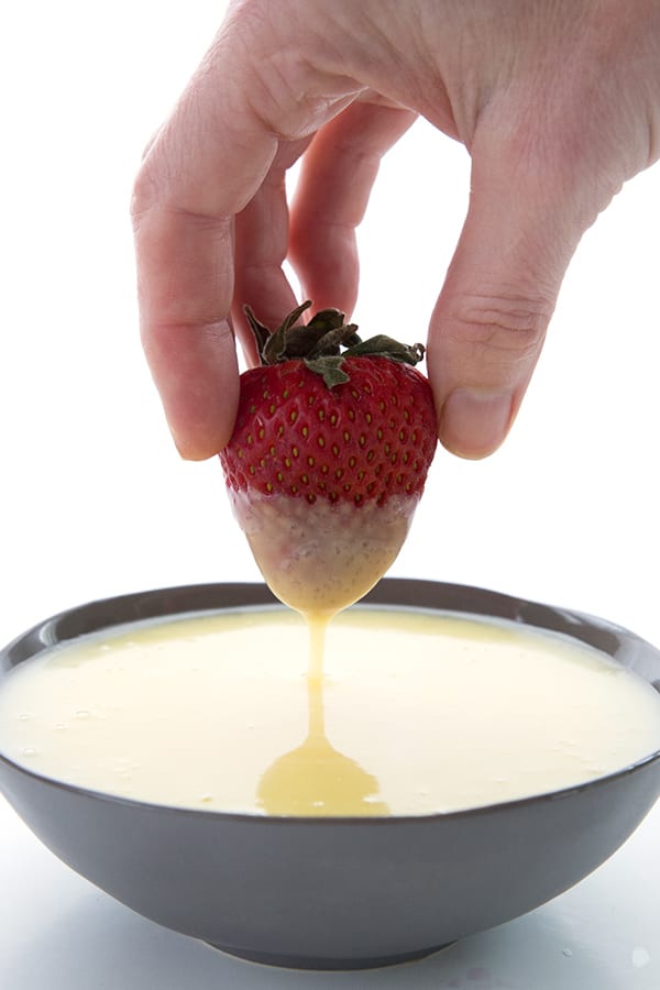 Sugar-free condensed milk in a bowl with a strawberry dipped into it.