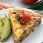 Titled image of a slice of Easy Taco Pie on a white plate with sliced avocado.