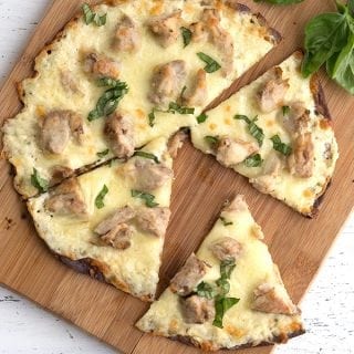 Chicken alfredo pizza on a cutting board with some pieces pulled apart