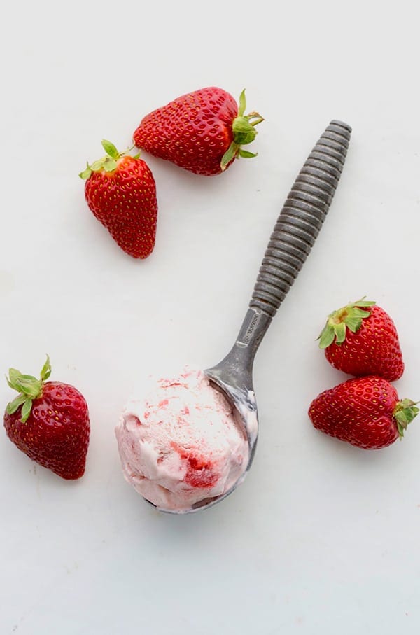 Top down photo of a scoop of keto strawberry ice cream with strawberries around it.