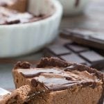Mini Low Carb Chocolate Cheesecake slice on a brown table with dishes in the background