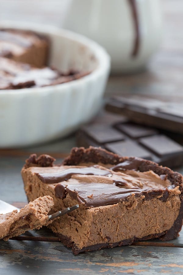 Mini Low Carb Chocolate Cheesecake slice on a brown table with dishes in the background