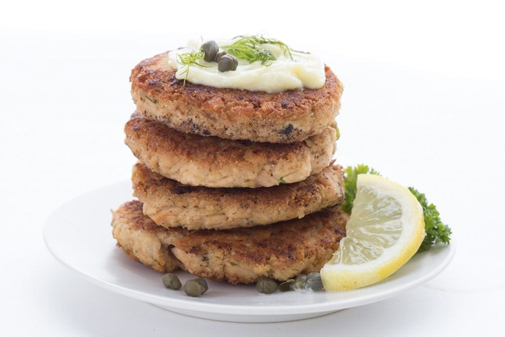 Lemon Dill Tuna Patties in a stack with mayo, capers, and dill