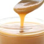 Close up shot of sugar free caramel sauce being drizzled from a spoon into a jar.