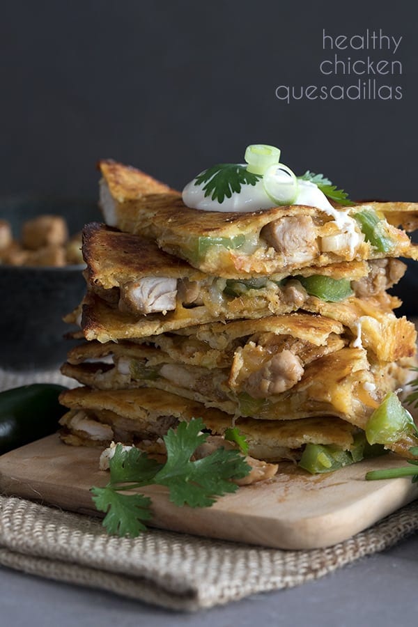 Easy Keto Chicken Quesadillas in a stack on a cutting board with sour cream on top.