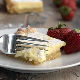 A fork going into a piece of keto gooey butter cake on a white plate