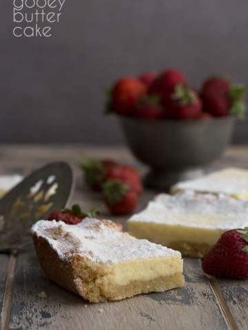 Keto Gooey Butter Cake slice on a wooden table with strawberries in the background