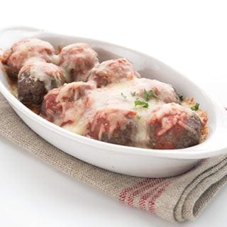 Oval white dish with meatball parmesan on a burlap napkin