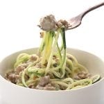 Easy keto alfredo sauce with sausage and zucchini noodles in a bowl and on a fork.