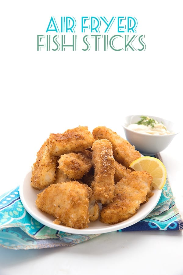 Air fryer fish sticks on a plate with lemon.