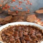 Titled image of The Best Keto Pecan Pie in a white pie dish, sitting on a plaid orange and brown napkin.