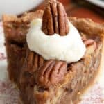 Titled image close up of a slice of keto pecan pie with whipped cream on top.