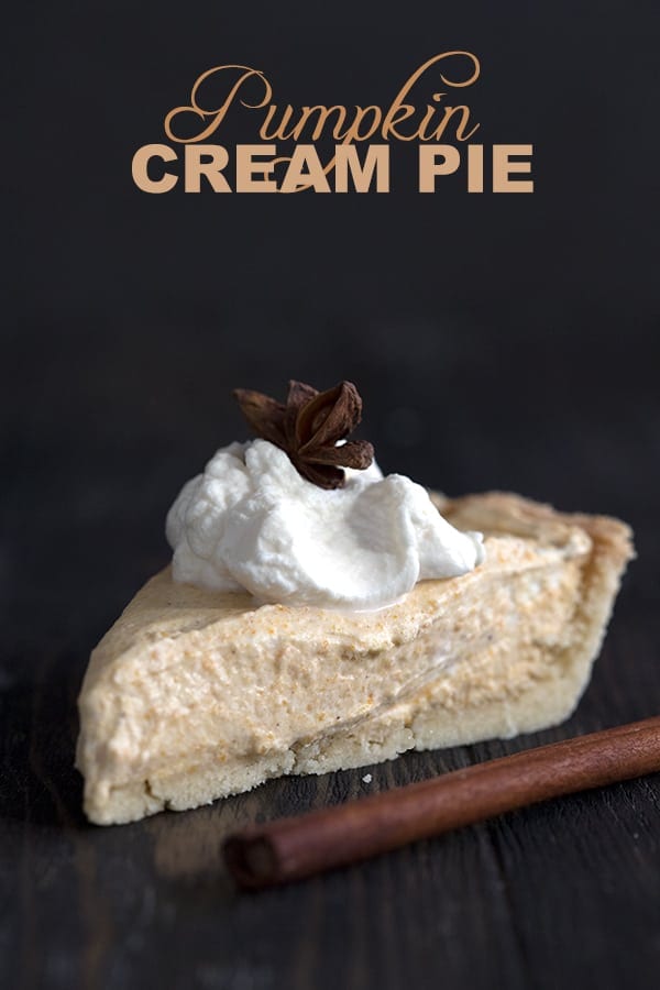 Keto Pumpkin Cream Pie - a slice of pie on a dark table with whipped cream and cinnamon sticks.