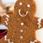 Close up shot of a keto gingerbread man leaned up against a glass of milk.