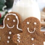 Titled image of two keto gingerbread cookies leaning up against a jar of milk.