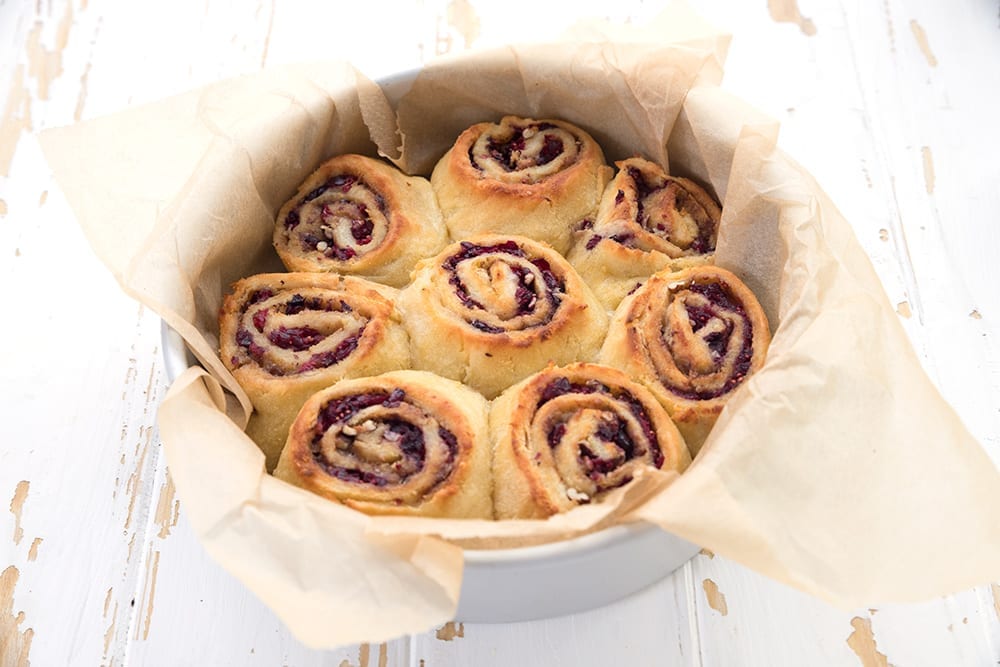 Baked keto cranberry cinnamon rolls in a round cake pan.