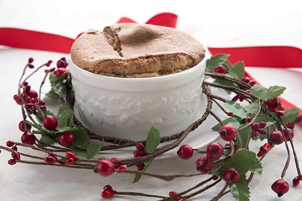 Low Carb Gingerbread Souffle in a white ramekin with red berries around it