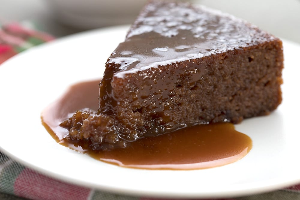 A slice of low carb sticky toffee pudding on a white plate