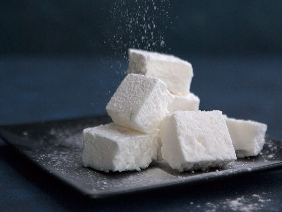 A pile of homemade marshmallows on a black plate