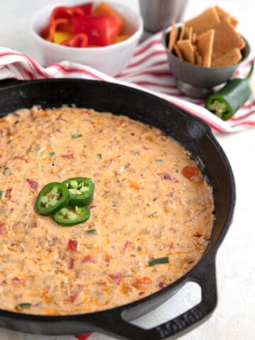 Sausage Cheese Dip in a cast iron skillet with sliced jalapeños on top.