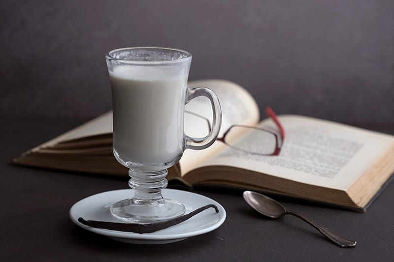Keto White Hot Chocolate in a glass in front of a book with glasses