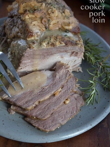Easy slow cooker pork loin roast on a gray plate with sauce