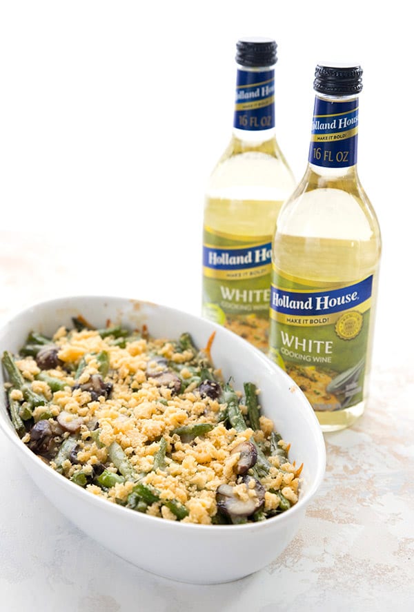 Green bean casserole with two bottles of white cooking wine in the background