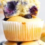 Titled image of a stack of Keto Blueberry Muffins with the top one broken open to show the inside.