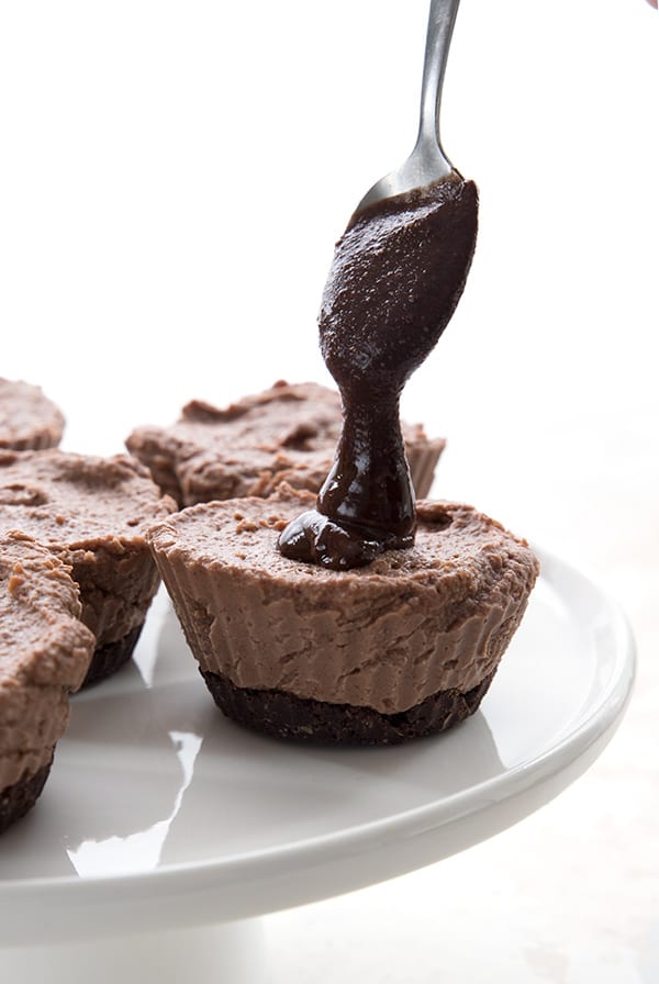 Drizzling homemade chocolate hazelnut spread on mini cheesecakes
