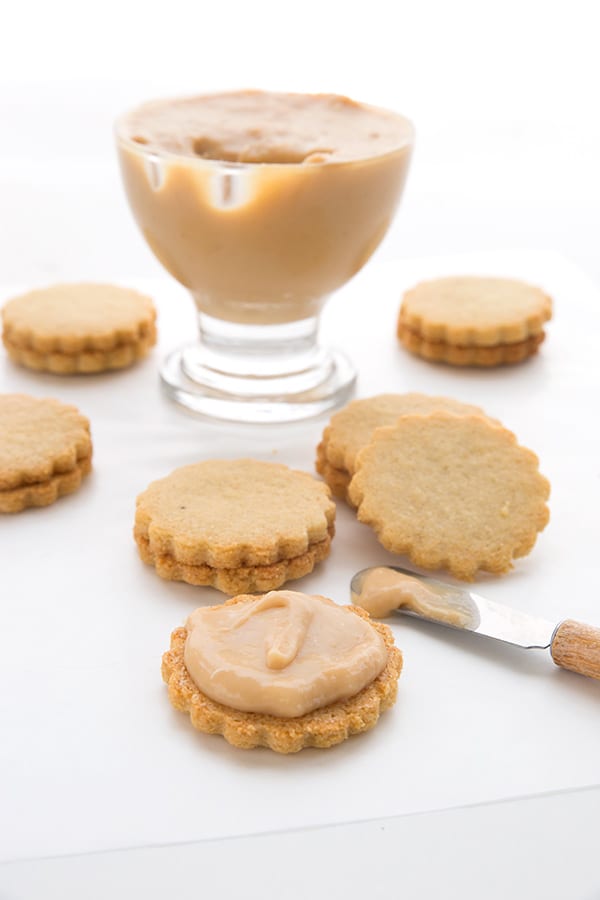 Sugar free dulce de leche being spread on keto cookies for alfajores