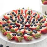 A platter full of patriotic cheesecake stuffed strawberries